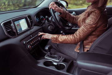 woman driving car, summer autumn forest, turns volume on off radio, increases adjustment air conditioner, activates button. Automatic transmission. Right-hand drive left-hand. Steering wheel right.