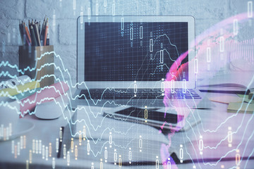 Stock market graph on background with desk and personal computer. Double exposure. Concept of financial analysis.