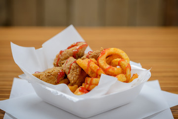 Chicken nuggets and curly fries to take away in polystyrene tub. With copy space above.