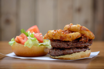 Double stack beef burger with onion rings, salad and bbq sauce, open.