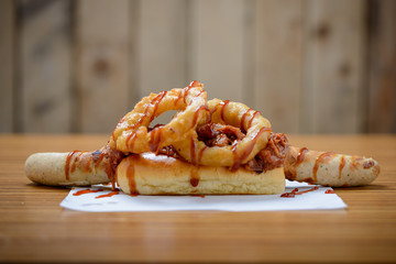 Jumbo hotdog with onion rings and ketchup in a brioche roll