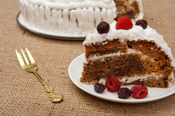 Sliced homemade biscuit cake decorated with whipped cream on plates.
