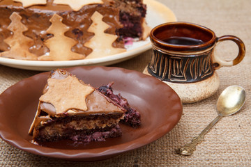 Chocolate cake on the plate and cup of coffee on the sackcloth