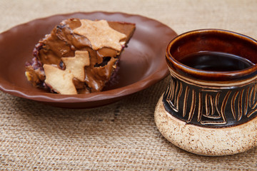 Chocolate cake on the plate and cup of coffee on the sackcloth
