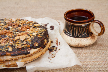 Chocolate cake on the plate and cup of coffee on the sackcloth