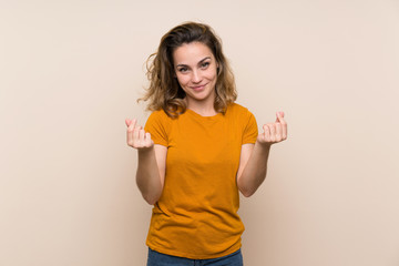 Young blonde girl over isolated background making money gesture