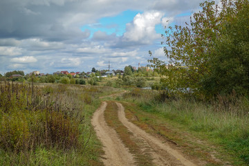 Russian rural landscape in the fall, village houses near the forest. Sky with rain clouds