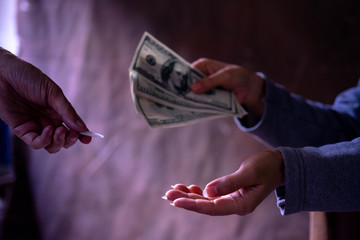 Woman hand with dollar banknotes buying drugs from a drug dealer, buying a dose of cocaine or...