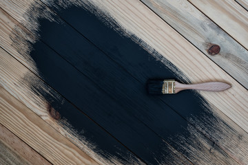Partially painted wooden boards in black. Soiled brush, process. Unfinished work. Space for text