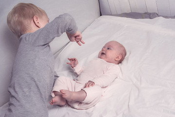 Blond older brother plays with his little sister. Child interaction