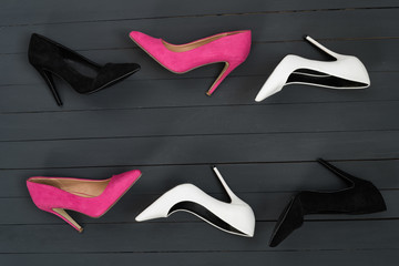 Women's high heel shoes in different colors. Black wood background. Fashion concept