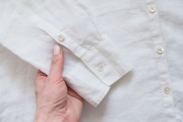 Sleeve of white shirt in female hand. Clothes concept. Details of clothes