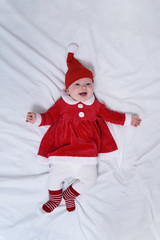 Portrait of cute little girl in a santa hat and a red dress. Lying on white background. Christmas concept