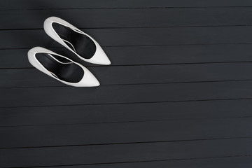 White female shoes on a black wooden background. Fashion concept. Copy space