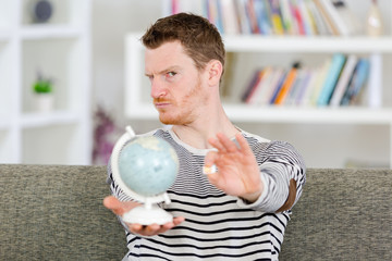 young man holding globe and sim card at home