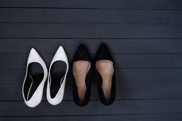 Black and white female shoes on a black wooden background. Fashion concept