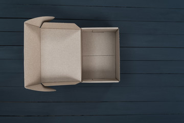 Empty open cardboard box on black wooden background. Delivery concept. Top view