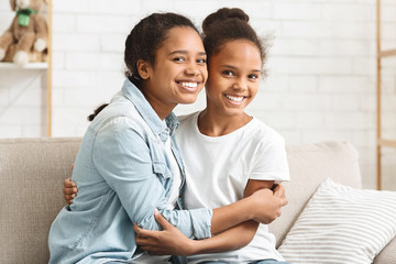 Two lovely african american sisters hugging at home