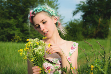 Portrait of a young happy smiling girl in a cotton dress with a bouquet of wildflowers