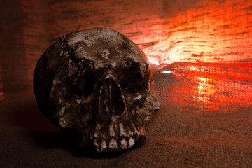 Human Skull with red light on brown textile background , Halloween decorations concept
