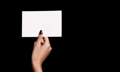 hand holding white card on black background - copyspace