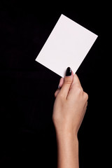 hand holding white card on black background - copyspace