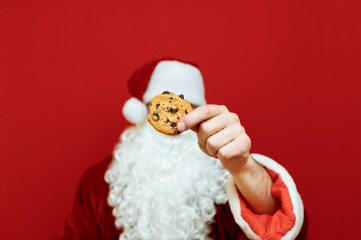 Closeup photo of Christmas cookies in Santa Claus hands isolated on red background. Christmas concept. Background.