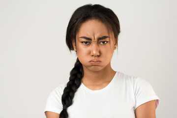 Angry afro girl blowing her cheeks, grey background