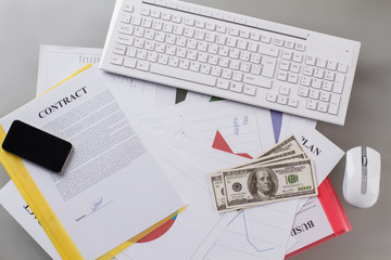 Documents on tabletop. Money and cellphone on signed contract. Keyboard and mouse. Business concept.