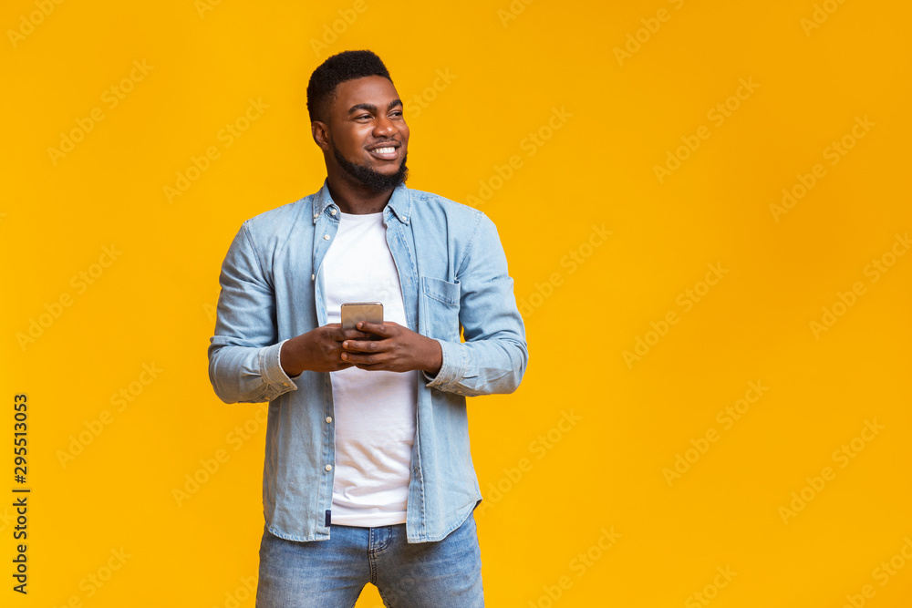 Poster handsome guy holding smartphone and looking aside at copy space