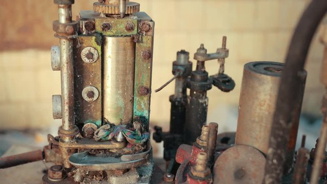many old scrap, faulty, rusted mechanism, old machine from the factory, gears, with buttons on which lie a lot of rubber belts, slow motion, close up