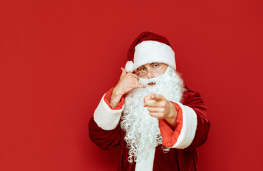 Fototapeta na wymiar Santa Claus show gestures Call me. Isolated on red background. New Year and Christmas concept. X-mas. Copy space