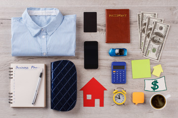 Busy person pattern on wooden table. Shirt, different personal and office stuff. Usual things around person.