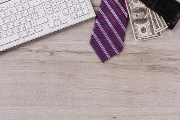 Obraz premium Keyboard on table close up. Striped tie and wallet full of money. Office worker's salary.