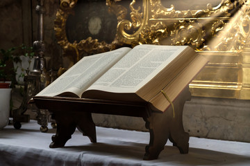 Open bible illuminated by sunbeams on an altar
