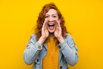 Redhead woman over isolated yellow background shouting with mouth wide open