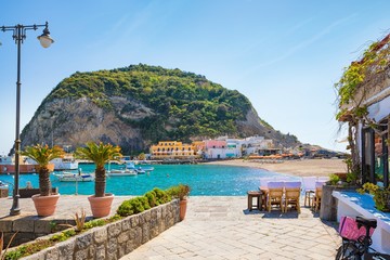 Beautiful coast of village Sant'Angelo, giant green rock in blue sea near Ischia Island, Italy. - obrazy, fototapety, plakaty