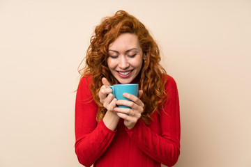 Redhead woman with turtleneck sweater holding hot cup of coffee