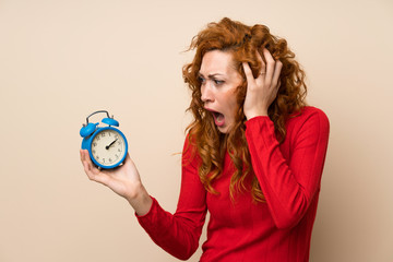 Redhead woman with turtleneck sweater holding vintage alarm clock