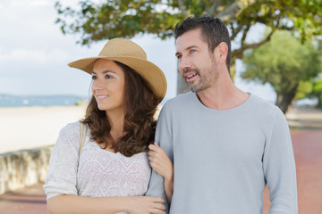 happy couple standing against a beach side in summer