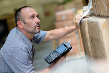 worker with portable barcode scanner in warehouse - obrazy, fototapety, plakaty
