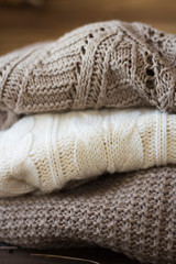Stack of cozy knitted sweaters on a wooden table. Retro style. Warm concept. close up