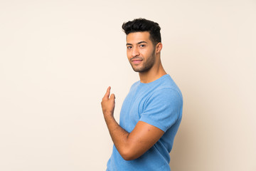 Young handsome man over isolated background pointing back