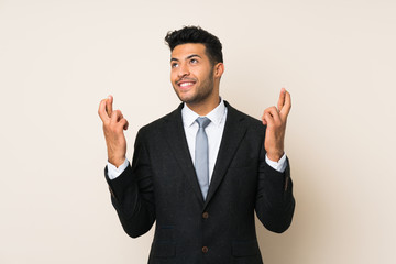 Young handsome businessman man over isolated background with fingers crossing