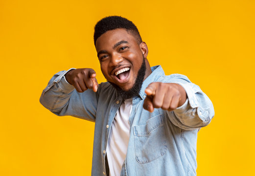 Cheerful african american man pointing fingers at camera