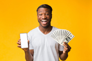 Afro Guy Holding Smartphone And Money Standing On Yellow Background