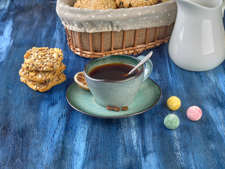 Porcelain cup with black coffee and shortbread.Are worth on backdrop of cold tones. 