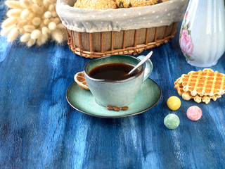 Porcelain cup with black coffee and shortbread.Are worth on backdrop of cold tones. 