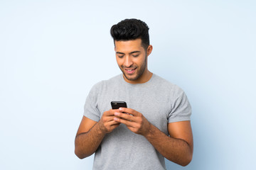 Young handsome man over isolated background sending a message or email with the mobile