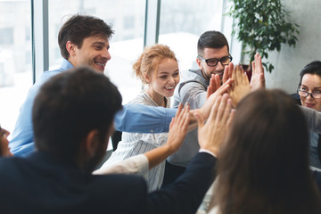 Motivated successful business team giving high five